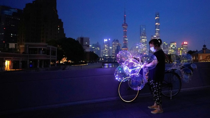 Hemat Listrik, Situs Ikonik di China Gelap Gulita A woman sells balloons on a bridge near the Bund amid a heatwave warning, as Shanghai switches off lights along a popular waterfront to conserve energy in Shanghai, China, August 22, 2022. REUTERS/Aly Song TPX IMAGES OF THE DAY