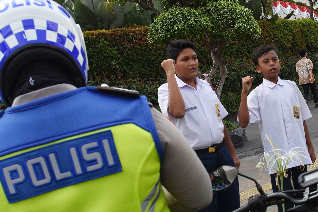 Dua pelajar SMP terjaring razia di kawasan Bundaran HI, Jakarta, Selasa (23/8/2022). Polisi memberikan hukuman tilang berupa menyanyikan lagu Indonesia Raya kepada kedua pelajar tersebut karena tidak memiliki SIM dan membawa STNK serta tidak mengenakan helm saat berkendara. ANTARA FOTO/Indrianto Eko Suwarso/hp.