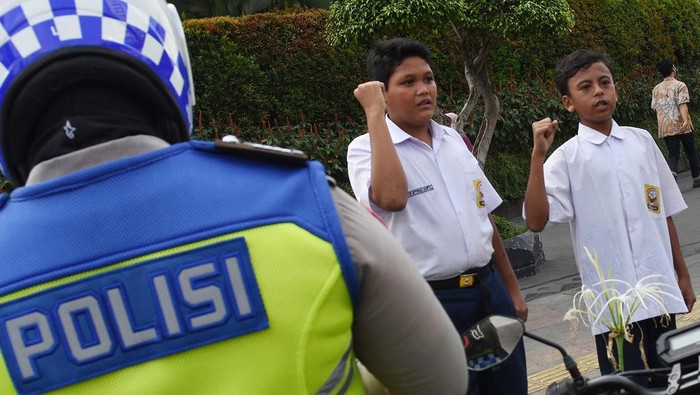Dua pelajar SMP terjaring razia di kawasan Bundaran HI, Jakarta, Selasa (23/8/2022). Polisi memberikan hukuman tilang berupa menyanyikan lagu Indonesia Raya kepada kedua pelajar tersebut karena tidak memiliki SIM dan membawa STNK serta tidak mengenak