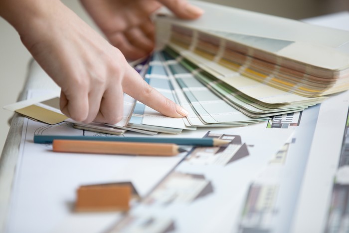 Pilih Arsitek atau Desainer Interior? Female architect working at home.She looking at blueprint.