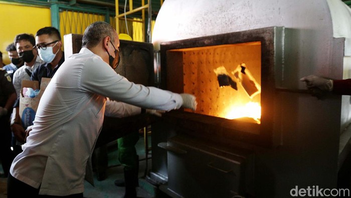 Wadirtipid Narkoba Bareskrim Polri, Kombes Pol Jayadi (berbaju putih) memasukkan salah satu barang bukti narkotika ke dalam incinerator (alat pembakar) di Instalasi Kesling, RSPAD Gatot Soebroto, Jakarta, Rabu (24/8/2022). Bareskrim Polri memusnahkan barang bukti berupa sabu sebanyak 8.742,2 gram, ganja 295.363 gram, serta 29.083 butir pil ekstasi dari 13 kasus dengan total 28 tersangka dari Jabodetabek, Lampung, Aceh, Jambi, dan Cirebon selama periode operasi 25 Mei 2022 hingga 20 Juli 2022.