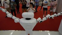 Seorang anak mencoba mengendalikan lengan robot dengan gerakan tangannya.