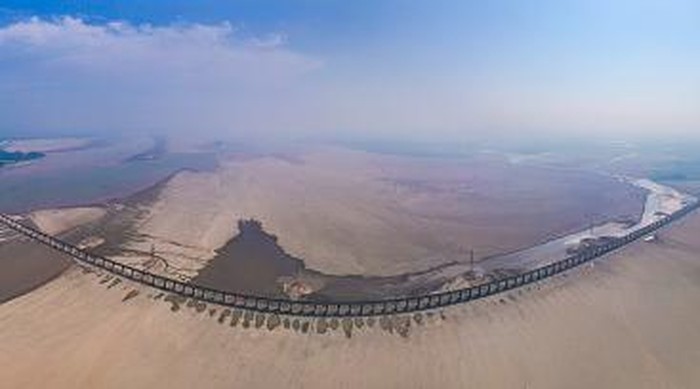 Jalur Kereta Api Membelah Danau yang Mengering di China JIUJIANG, CHINA - AUGUST 24, 2022 - Aerial photo taken on Aug 24, 2022 shows the dry water area near Poyang Lake Bridge in Jiujiang City, East China's Jiangxi Province. Since July, the water level of Poyang Lake, the largest freshwater lake in China, has continued to drop due to high temperature and little rainfall, breaking the record of entering dry season and low dry season for the first time since 1951. As of 0:00 on August 25, the water level of Xingzi station in Poyang Lake was 9.53 meters. (Photo credit should read CFOTO/Future Publishing via Getty Images)