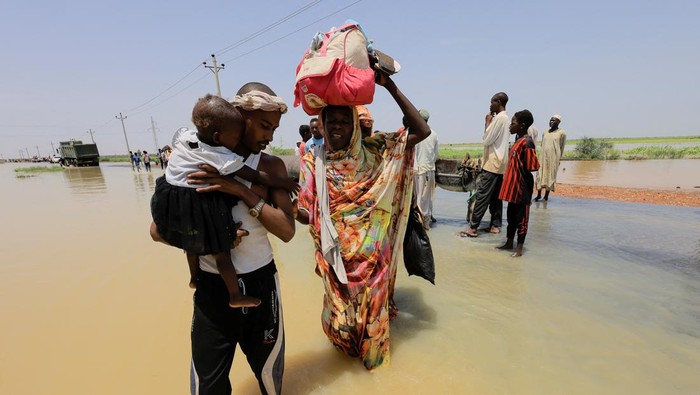 Melihat Proses Evakuasi Anak-anak Korban Banjir di Sudan People cross the water during a flood in Al-Managil locality, Sudan, August 23, 2022. REUTERS/Mohamed Nureldin Abdallah