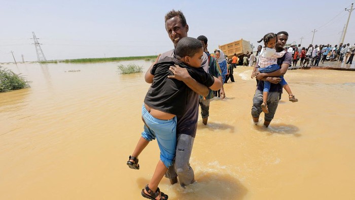 People cross the water during a flood in Al-Managil locality, Sudan, August 23, 2022. REUTERS/Mohamed Nureldin Abdallah