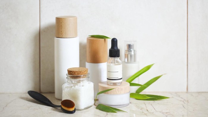 Face cream, serum, lotion, moisturizer and sea salt  among bamboo leaves in the bath