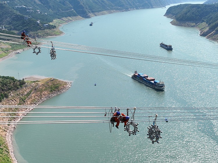 Aksi Petugas China Saat Sambungkan Listrik dari Barat ke Timur YICHANG, CHINA - AUGUST 25, 2022 - Aerial photo taken on Aug 25, 2022 shows workers installing spacers across the Yangtze River on the ultra-high voltage