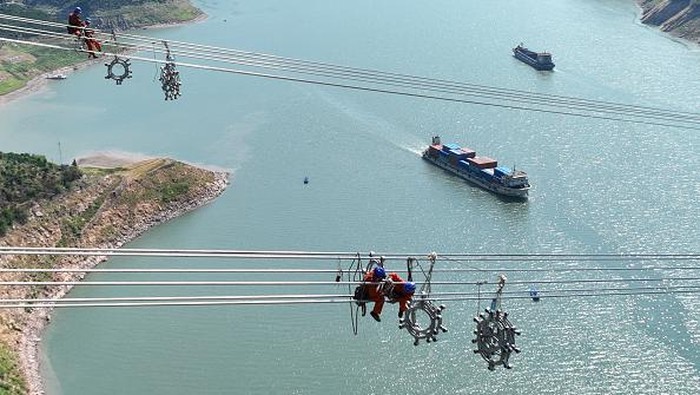 YICHANG, CHINA - AUGUST 25, 2022 - Aerial photo taken on Aug 25, 2022 shows workers installing spacers across the Yangtze River on the ultra-high voltage 