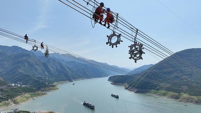 Aksi Petugas China Saat Sambungkan Listrik dari Barat ke Timur YICHANG, CHINA - AUGUST 25, 2022 - Aerial photo taken on Aug 25, 2022 shows workers installing spacers across the Yangtze River on the ultra-high voltage