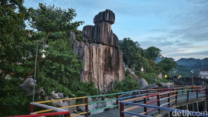 Perahu Nelayan melintas melewati Batu Tumpak Tiga di Tarempa, Kabupaten Kepulauan Anambas, Kepulauan Riau, Senin (1/8/2022). Batu Tumpak Tiga adalah batu raksasa yang bersusun tiga yang unik. Batu-batu ini sengaja dibiarkan tertata bertumpuk.
