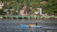 Perahu Nelayan melintas melewati Batu Tumpak Tiga di Tarempa, Kabupaten Kepulauan Anambas, Kepulauan Riau, Senin (1/8/2022). Batu Tumpak Tiga adalah batu raksasa yang bersusun tiga yang unik. Batu-batu ini sengaja dibiarkan tertata bertumpuk.  
