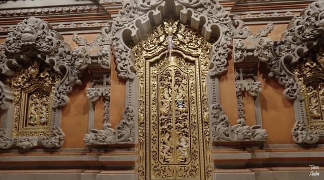 Pintu masuk tetap konsisten dengan ukiran Bali yang memukau. Warna emas memberi sentuhan mewah. (Foto: YouTube/Tiara Andini)