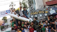 Anak-anak begitu antusias melihat dan berfoto di roket yang dipamerkan pasukan Jihad Islam.