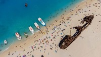 Foto udara menunjukkan ramainya wisatawan yang berkunjung ke pantai kapal karam.