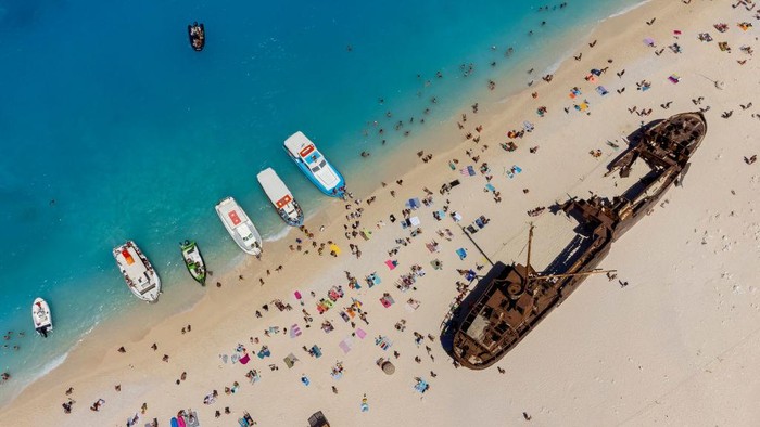 Terhipnotis Pesona Pantai Kapal Karam di Yunani ZAKINTHOS, GREECE - AUGUST 09: Aerial view of Navagio Beach or Shipwreck Beach on August 09, 2022 in Zakinthos, Greece. On 2 October 1980, the ship ran aground in the waters during stormy weather and bad visibility. Some rumours claim the ship was smuggling contraband from Turkey with a freight of contraband cigarettes headed for Italy. The ship was abandoned and still rests buried in the limestone gravel of the beach named Shipwreck. In 2018, the beach was named as the world's best beach in a poll by journalists. (Photo by Athanasios Gioumpasis/Getty Images)