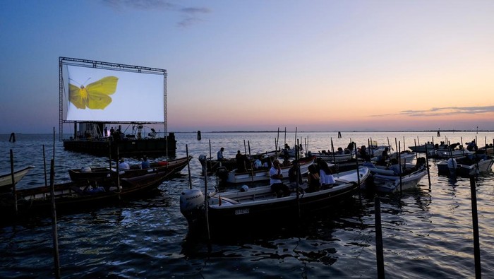 Unik, Begini Sensasi Nonton di Bioskop Terapung Italia People on boats attend a movie screening at a float-in cinema during the 'Floating Cinema β Unknown Waters' event, taking place on the waters of the Venetian lagoon, in Venice, Italy. August 25, 2022. REUTERS/Manuel Silvestri