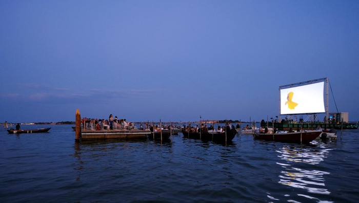 Unik, Begini Sensasi Nonton di Bioskop Terapung Italia People on boats attend a movie screening at a float-in cinema during the 'Floating Cinema β Unknown Waters' event, taking place on the waters of the Venetian lagoon, in Venice, Italy. August 25, 2022. REUTERS/Manuel Silvestri