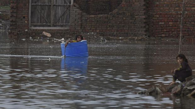 Seorang pria menggunakan drum plastik menyeberangi daerah banjir setelah hujan muson lebat di Jacobabad, provinsi Sindh, Pakistan, Jumat (26/8/2022). Pemerintah Pakistan mengumumkan keadaan darurat untuk menangani banjir musim hujan yang berdampak terhadap lebih dari empat juta warga yang mengakibatkan 34 orang tewas di negara itu. (Photo by ASIF HASSAN/AFP via Getty Images)
