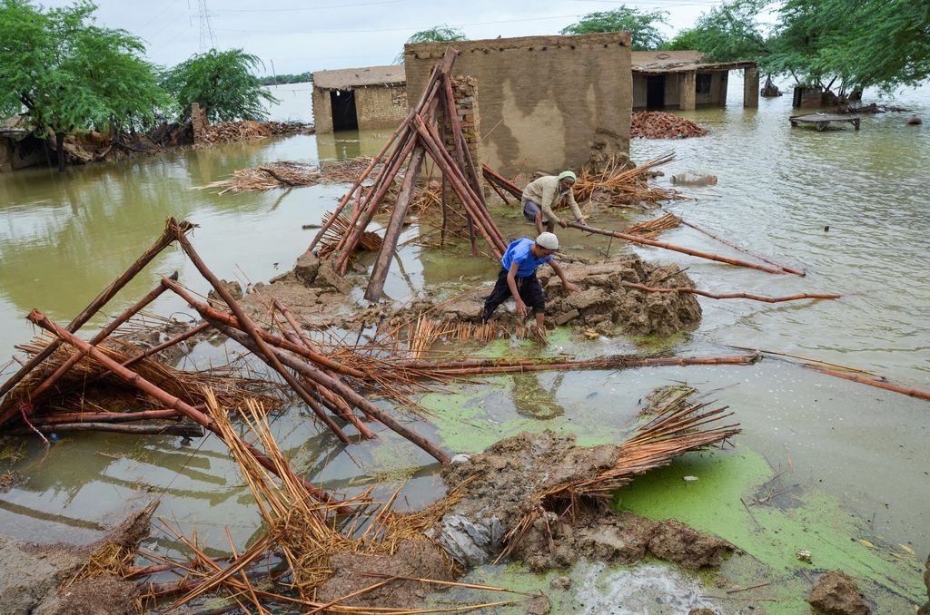 Flood victims receive boiled rice from relief workers, after taking refuge on a motorway, following rains and floods during the monsoon season in Charsadda, Pakistan August 27, 2022. REUTERS/Fayaz Aziz