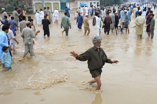 Flood victims receive boiled rice from relief workers, after taking refuge on a motorway, following rains and floods during the monsoon season in Charsadda, Pakistan August 27, 2022. REUTERS/Fayaz Aziz