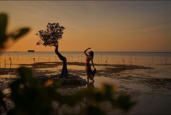 Masih dengan latar belakang sunset yang indah, Ranty Maria juga tampak berpose sendirian di pinggir pantai. Terlihat Ranty yang berdiri dengan salah satu tangan yang diangkat ke atas, sementara lainnya memegang bagian belakang rok panjang yang dikenakannya. Foto: Instagram/@rantymaria