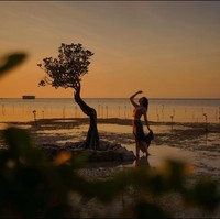 Masih dengan latar belakang sunset yang indah, Ranty Maria juga tampak berpose sendirian di pinggir pantai. Terlihat Ranty yang berdiri dengan salah satu tangan yang diangkat ke atas, sementara lainnya memegang bagian belakang rok panjang yang dikenakannya. Foto: Instagram/@rantymaria