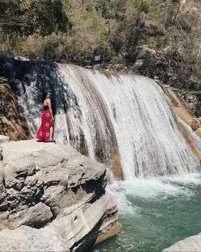 Begini potret Ranty Maria saat berpose di samping air terjun Tanggedu. Sambil mengenakan tanktop hitam dan rok panjang merah berbelahan samping, penampilan Ranty Maria tampak mempesona. Foto: Instagram/@rantymaria
