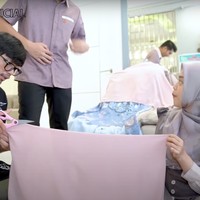 Demi Moana bisa mengenakan kerudung saat photoshoot bersama, Ricis sampai harus menggunting bahan kerudung yang akan dikenakan oleh Moana agar pas di kepalanya. Dengan bantuan salah satu timnya, Ricis pun memotong sendiri kerudung yang akan dikenakan sang anak. Foto: YouTube/Ricis Official