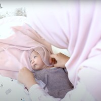 Dengan hati-hati Ricis berusaha memasangkan kerudung di kepala anaknya. Kerudungnya itu tampak berwarna senada dengan baju yang dikenakan oleh baby Moana. Foto: YouTube/Ricis Official