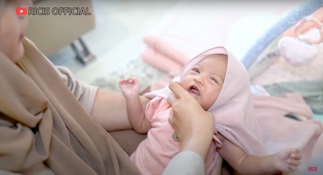 Masih berusia 1 bulan, baby Moana anak Ria Ricis dan Teuku Ryan rupanya sudah diajarkan untuk tampil tertutup dengan mengenakan hijab. Melalui salah satu video di YouTube miliknya, Ricis pun membagikan momen saat baby Moana mengenakan hijab. Foto: YouTube/Ricis Official