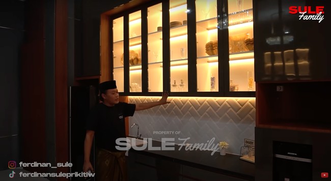 Dapur di lantai 2 rumah Sule makin terlihat mewah dan elegan dengan rak lemari kaca yang dilengkapi dengan lampu berwarna kuning. Rak lemari kaca itu tampak cukup besar dan terdiri dari 3 susun yang bisa digunakan untuk menyimpan peralatan dapur serta pajangan. Foto: YouTube/Sule Family