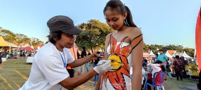 Seniman lukis Bali, Wayan Wirawan tengah melukis model body painting di Sanur Village Festival 2022.