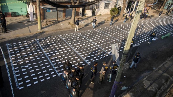 1242726347 Police stand guard over seized packages of cocaine displayed to the press in Rosario, Santa Fe province, Argentina on August 26, 2022. - Federal Police officers seized more than 1,600 kilos of cocaine, valued at some US$60 million, which were about to leave through the waterway to Dubai, authorities said. (Photo by AFP) (Photo by STR/AFP via Getty Images)