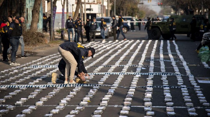 Police stand guard over seized packages of cocaine displayed to the press in Rosario, Santa Fe province, Argentina on August 26, 2022. - Federal Police officers seized more than 1,600 kilos of cocaine, valued at some US$60 million, which were about to leave through the waterway to Dubai, authorities said. (Photo by AFP) (Photo by STR/AFP via Getty Images)