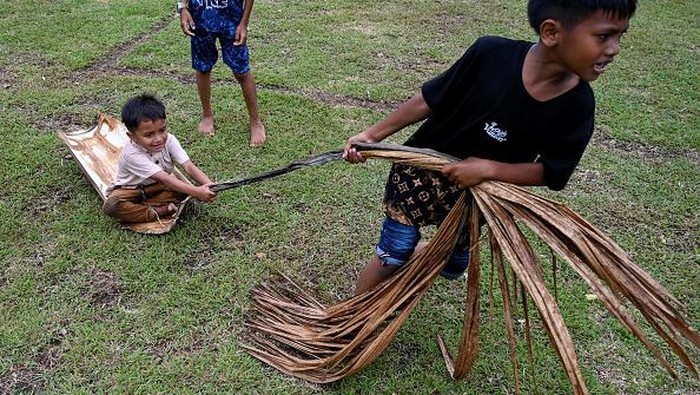 A man assists his child to play a traditional game during an eco-tourism village program in Lubok Sukon, Indonesias Aceh province on August 27, 2022. (Photo by CHAIDEER MAHYUDDIN / AFP) (Photo by CHAIDEER MAHYUDDIN/AFP via Getty Images)