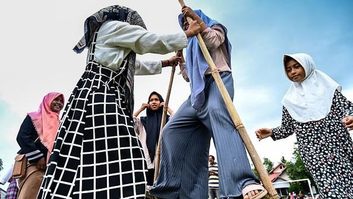 A man assists his child to play a traditional game during an eco-tourism village program in Lubok Sukon, Indonesia's Aceh province on August 27, 2022. (Photo by CHAIDEER MAHYUDDIN / AFP) (Photo by CHAIDEER MAHYUDDIN/AFP via Getty Images)