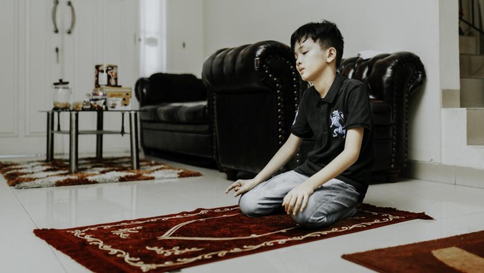 asian muslim kid is salah (doa) in home