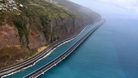 Pemandangan udara menunjukkan kendaraan yang melaju di Nouvelle Route du Littoral, Pulau Reunion, Prancis, Minggu (28/8/2022). Pulau ini berada di sebelah barat Pulau Madagaskar, Afrika.  