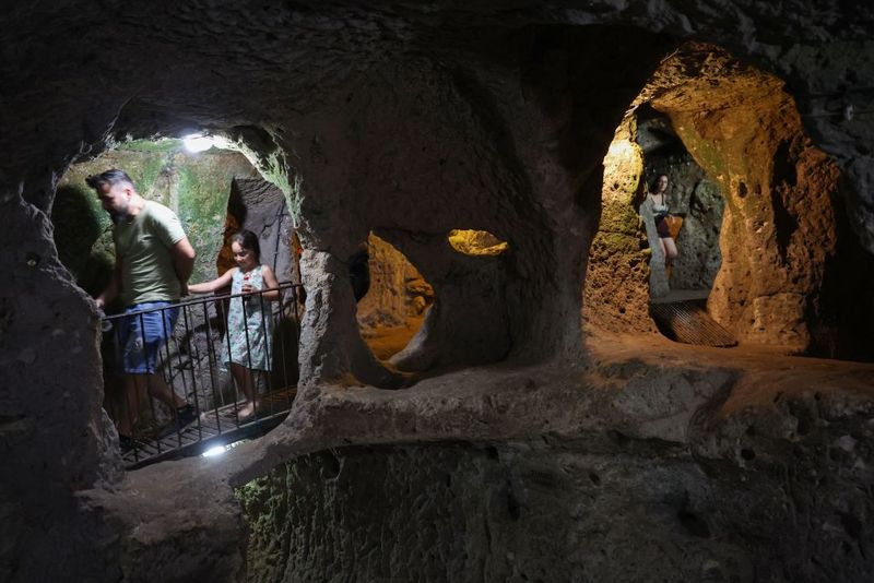 Tourists explore a passage in the Derinkuyu underground city, in Turkey's central Nevsehir province, on August 24, 2022. - The ancient city of Elengubu, known today as Derinkuyu, reaches the depth of 85m below the Earth's surface, and could accommodate up to 20,000 people. (Photo by OMAR HAJ KADOUR / AFP) (Photo by OMAR HAJ KADOUR/AFP via Getty Images)