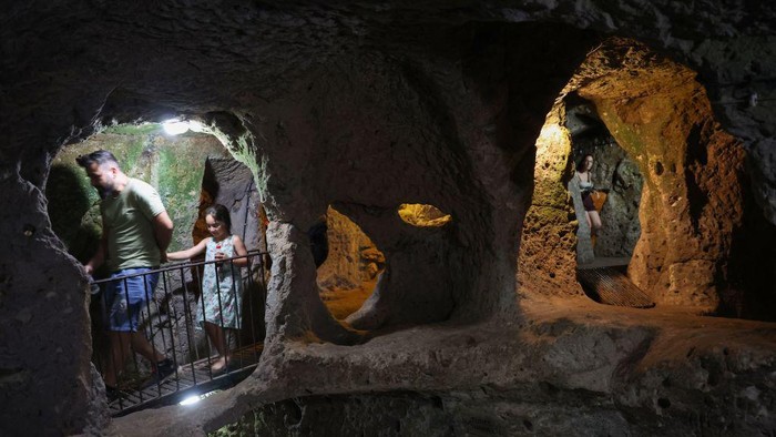 Tourists explore a passage in the Derinkuyu underground city, in Turkey's central Nevsehir province, on August 24, 2022. - The ancient city of Elengubu, known today as Derinkuyu, reaches the depth of 85m below the Earth's surface, and could accommodate up to 20,000 people. (Photo by OMAR HAJ KADOUR / AFP) (Photo by OMAR HAJ KADOUR/AFP via Getty Images)