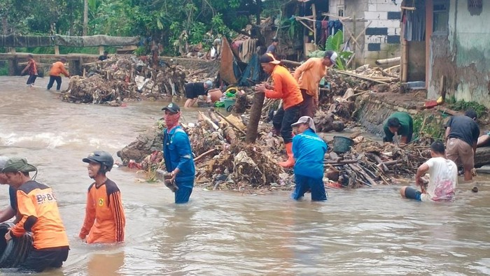 Petugs BPBD Kabupaten Bogor membersihkan pohon yang tumbang dan menyumbat Sungai Kalibaru.