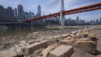 Bebatuan tersingkap di dasar sungai kering Sungai Jialing di Kota Chongqing, China barat daya, Jumat, (19/8/2022). Kapal-kapal merayap di tengah Sungai Yangtze pada Jumat setelah musim panas terkering dalam enam dekade membuat salah satu sungai terbesar menyusut menjadi hampir setengah lebar normalnya dan memicu perebutan untuk menahan kerusakan pada ekonomi yang lemah di tahun yang sensitif secara politik. (AP/Mark Schiefelbein)