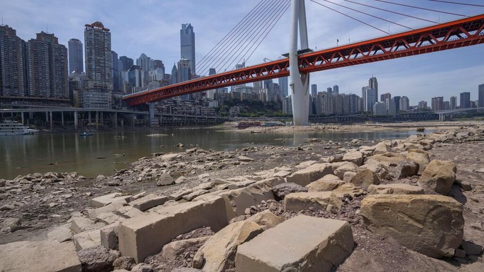 Rocks are exposed on the dry riverbed of the Jialing River in southwestern China's Chongqing Municipality, Friday, Aug. 19, 2022. Ships crept down the middle of the Yangtze on Friday after the driest summer in six decades left one of the mightiest rivers shrunk to barely half its normal width and set off a scramble to contain damage to a weak economy in a politically sensitive year. (AP Photo/Mark Schiefelbein)