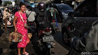 Seorang warga mencoba melintasi jalan yang sedang macet gegara pasar tumpah. Rute ini menjadi akses utama para pekerja yang tinggal di Kabupaten Bekasi menuju Jakarta.