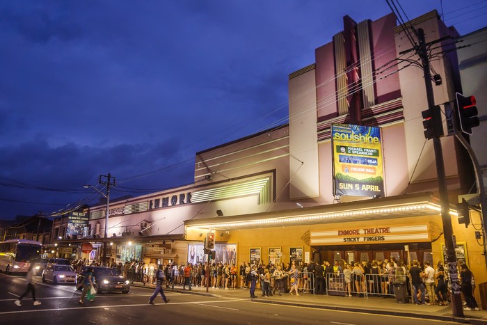 Sydney, Australia - March 21, 2015: A line of concertgoers outside the Enmore Theatre in Newtown at dusk. The art deco entertainment venue was first opened in 1908.