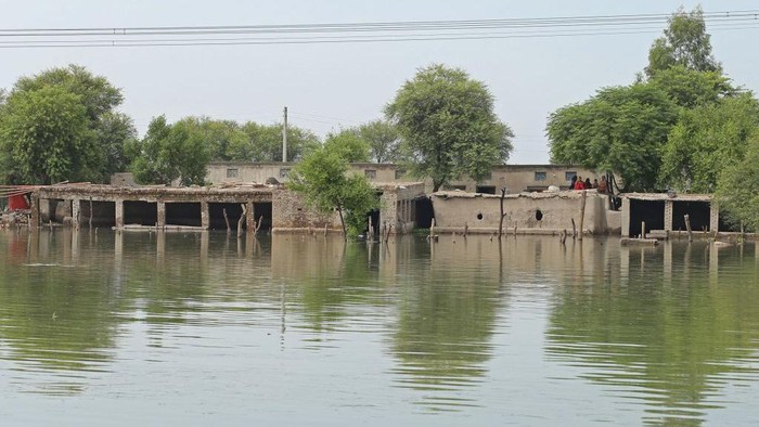 Women sit atop their mud house in a flood hit area following heavy monsoon rains in Dera Ghazi Khan district in Punjab province on August 29, 2022. - The death toll from monsoon flooding in Pakistan since June has reached 1,136, according to figures released on August 29 by the country's National Disaster Management Authority. (Photo by Shahid Saeed MIRZA / AFP) (Photo by SHAHID SAEED MIRZA/AFP via Getty Images)