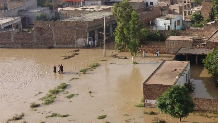 Residents wade through a flood hit area following heavy monsoon rains in Charsadda district of Khyber Pakhtunkhwa on August 29, 2022. - The death toll from monsoon flooding in Pakistan since June has reached 1,061, according to figures released on August 29, 2022, by the countrys National Disaster Management Authority. (Photo by Abdul MAJEED / AFP) (Photo by ABDUL MAJEED/AFP via Getty Images)