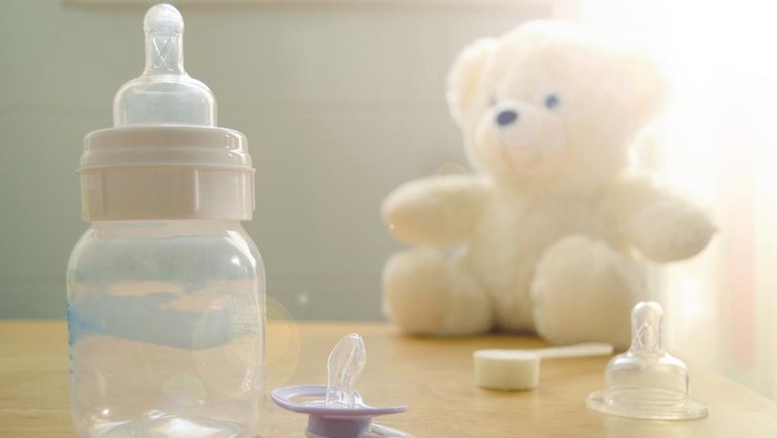Baby bottle, pacifier and a babys toy on a wooden table