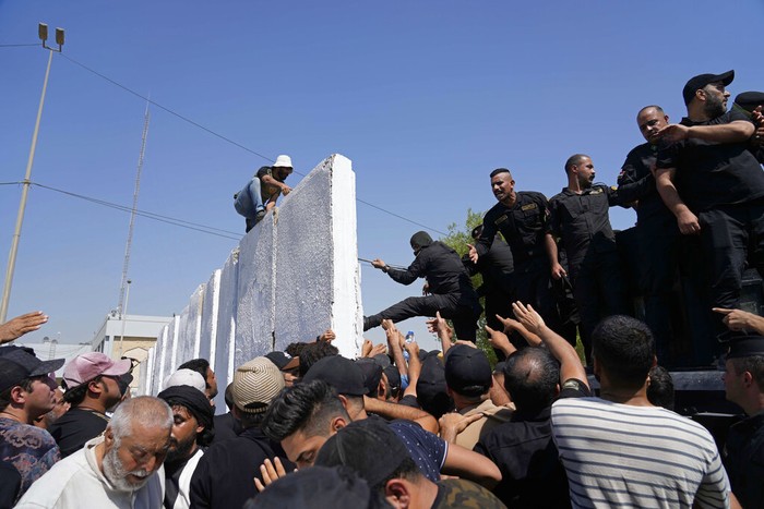 Iraqi security forces fire tear gas on followers of Shiite cleric Muqtada al-Sadr protesting inside the government palace grounds, in Baghdad, Iraq, Monday, Aug. 29, 2022. Al-Sadr, a hugely influential Shiite cleric announced he will resign from Iraqi politics and his angry followers stormed the government palace in response. The chaos Monday sparked fears that violence could erupt in a country already beset by its worst political crisis in years. (AP Photo/Hadi Mizban)