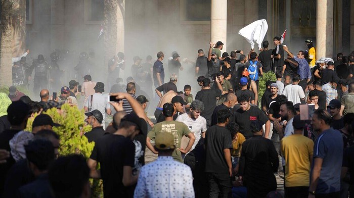 Iraqi security forces fire tear gas on followers of Shiite cleric Muqtada al-Sadr protesting inside the government palace grounds, in Baghdad, Iraq, Monday, Aug. 29, 2022. Al-Sadr, a hugely influential Shiite cleric announced he will resign from Iraqi politics and his angry followers stormed the government palace in response. The chaos Monday sparked fears that violence could erupt in a country already beset by its worst political crisis in years. (AP Photo/Hadi Mizban)